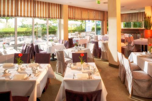 a restaurant with white tables and chairs and windows at Dorint Strandhotel Binz/Rügen in Binz