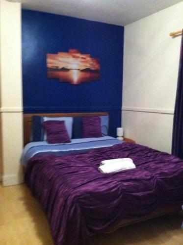 a bedroom with a purple bed with a blue wall at The Oasis Hotel in Harlow