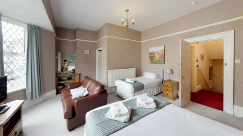 Habitación de hotel con 2 camas y sofá en The Tudor Guest House, en Plymouth