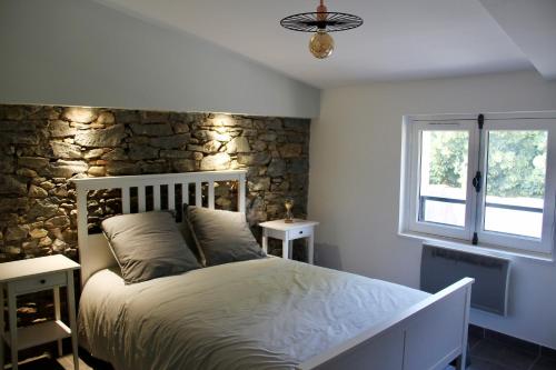 une chambre avec un lit et un mur en pierre dans l'établissement Le Voltaire, à Carcassonne
