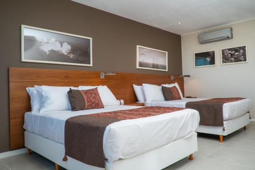ein Hotelzimmer mit 2 Betten und 2 Stühlen in der Unterkunft Orfeo Suites Hotel Sierras Chicas in Salsipuedes