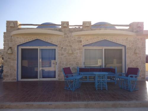 un patio con mesas azules y sillas en un edificio en Light House, en Marsa Alam