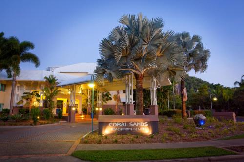 a sign in front of a building with palm trees at Coral Sands Beachfront Resort in Trinity Beach