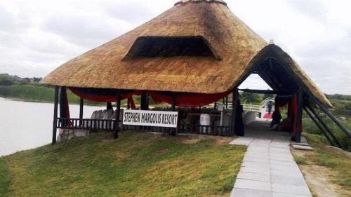 a hut with a thatched roof on top of a body of water at Stephen Margolis Resort in Harare