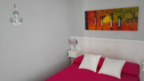 ベナルマデナにあるApartamento en Benalmadena costaの赤いベッドと壁に絵画が飾られたベッドルーム1室