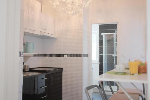a kitchen with white cabinets and a chandelier at Like-home Casa Prazeres in Lisbon