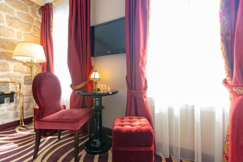 a living room with a red chair and a tv at Hotel Du Beaumont in Paris