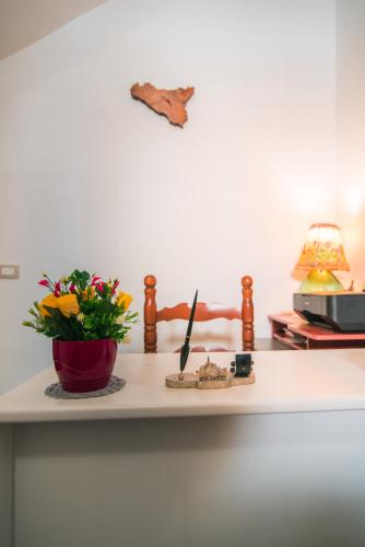 a table with a vase of flowers and a plant at B&B U PRUFISSURI in Avola