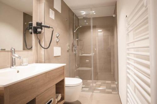 uma casa de banho com um chuveiro, um WC e um lavatório. em Hotel Mediterra em Uhldingen-Mühlhofen