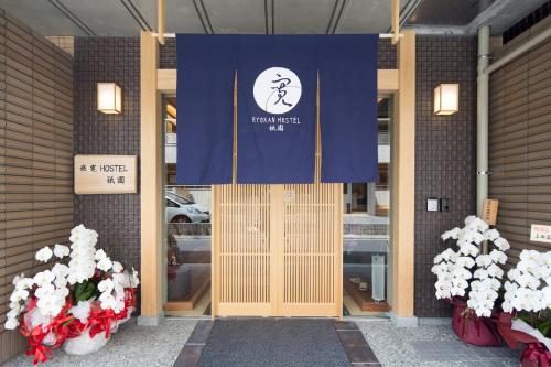una porta d'ingresso di un edificio con un cartello blu e bianco di Ryokan Hostel Gion a Kyoto