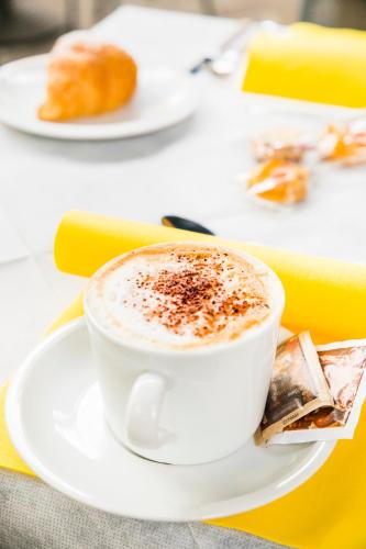 a cup of coffee on a white plate on a table at Hotel Raphael in Montecatini Terme