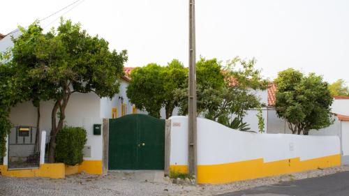 a white house with a green door and trees at Casa dos Avós in Villa Nogueira