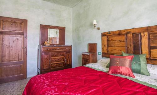 a bedroom with a large red bed with a wooden headboard at Le Casette Country House in Petricci
