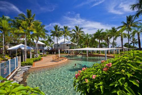 a pool at a resort with palm trees at Coral Sands Beachfront Resort in Trinity Beach