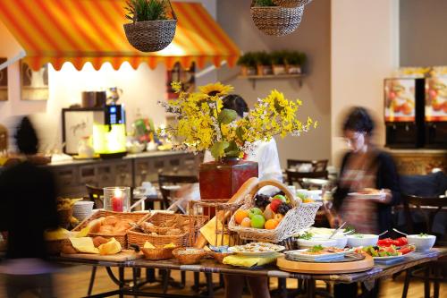 een tafel vol eten en een vrouw in de keuken bij Hotel Chateau Kurfürstendamm in Berlijn