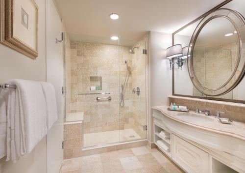 a bathroom with a shower and a sink and a mirror at The Windsor Court in New Orleans