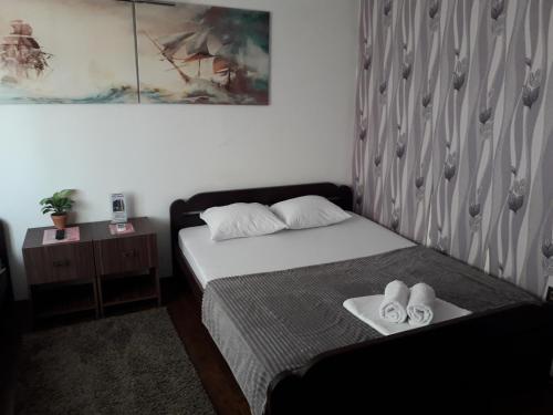 a bedroom with a bed with two pairs of slippers at Guest House Vila Salute in Niš