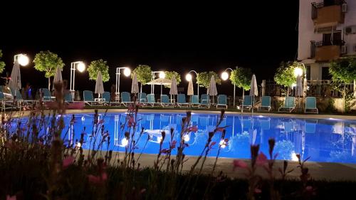 una piscina por la noche con sillas y luces en Bel Conti Hotel, en Durrës