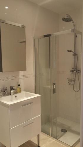 a white bathroom with a shower and a sink at Le Relais de la Praya in Lège-Cap-Ferret