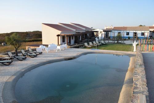 a large swimming pool with chairs and a house at Barranco da Fonte in Chabouco