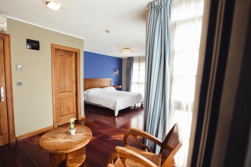 a bedroom with a bed and a table and chairs at Hotel El Sella in Cangas de Onís