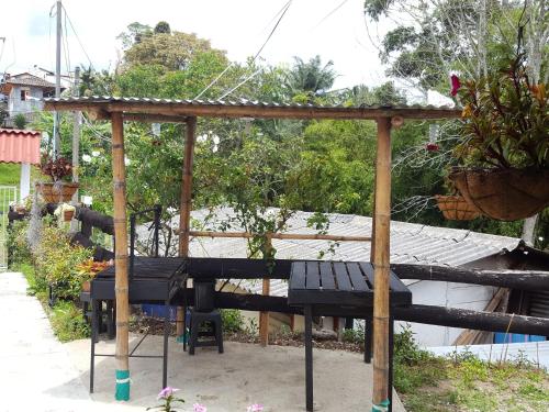 a wooden pergola with a picnic table in a garden at Hostal y Camping Los Girasoles in Salento