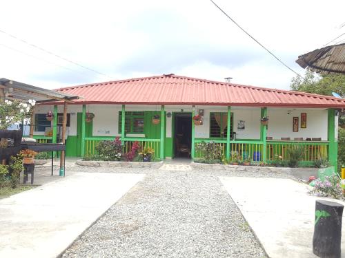 a green and white building with a red roof at Hostal y Camping Los Girasoles in Salento