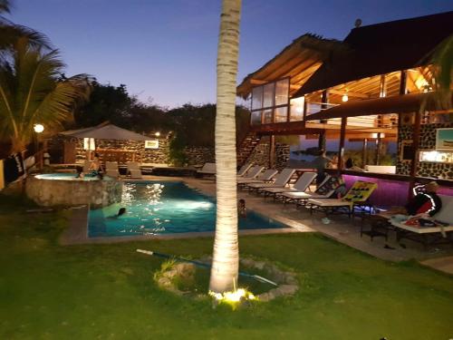 a pool with a palm tree next to a building at Hotel Villa Sirena in Vichayito