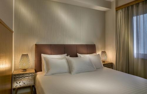 um quarto com uma cama com almofadas brancas e uma janela em Acropolis View Penthouse em Atenas