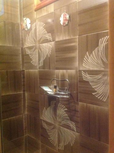 MianeにあるB&B Casa Lisaの茶色のタイルのシャワー&白い葉が描かれたシャワー
