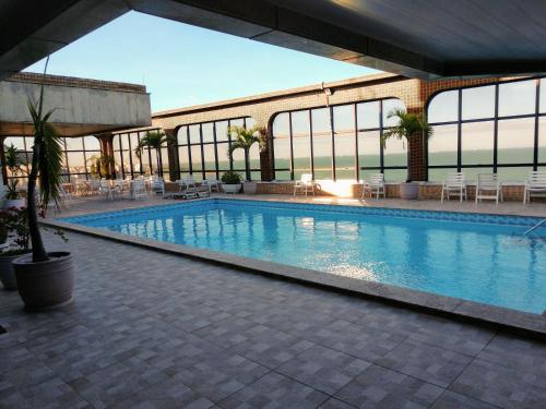 una gran piscina con sillas y mesas en un edificio en Flat Pasárgada 812, Free Bikes, pé na praia en Vila Velha