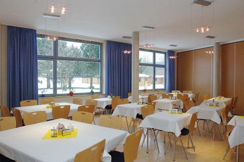 un restaurante con mesas y sillas blancas y ventanas en A&S Ferienzentrum Schwerin, en Schwerin