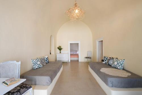 a living room with two beds and a chandelier at DeltaMi Santorini in Pirgos
