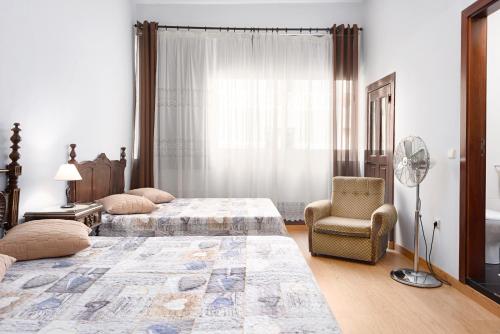 1 dormitorio con 2 camas, silla y ventilador en Almada Guest House, en Oporto