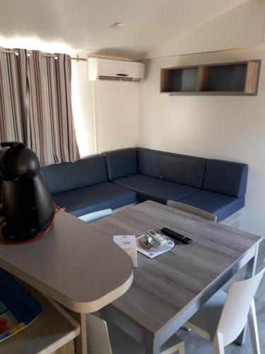 uma sala de estar com um sofá azul e uma mesa em Mobil home florida - camping les cigales - 4 étoiles em Le Muy