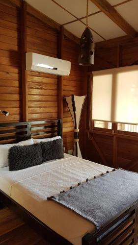 1 dormitorio con 1 cama grande y paredes de madera en Ecolodge Luna del Rio en El Castillo de La Concepción