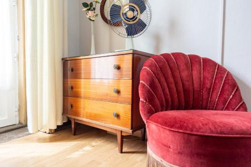 a red chair next to a dresser and a fan at Almada Guest House in Porto