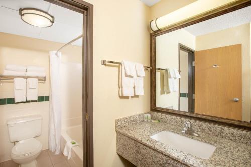 a bathroom with a sink and a toilet and a mirror at AmericInn by Wyndham Kearney in Kearney