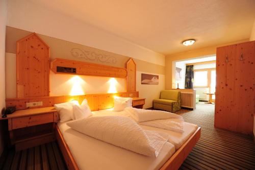 a hotel room with a large bed and a chair at Hotel Toni in Galtür