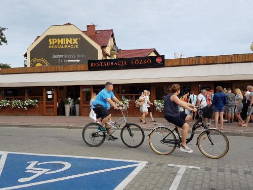 a couple of people riding bikes down a street at Apartament 316 w Domu Zdrojowym in Jastarnia