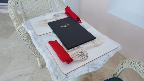 une table avec une chaise, un livre et des serviettes rouges dans l'établissement Ocean West Boutique Hotel, à Nassau