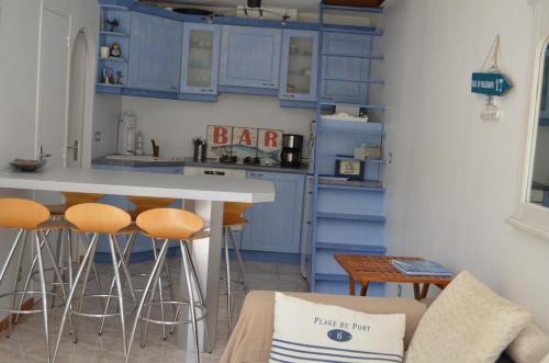 une cuisine avec des placards bleus et un bar avec des tabourets dans l'établissement Coquette Maisonnette Centre Ville La Londe Les Maures, à La Londe-les-Maures