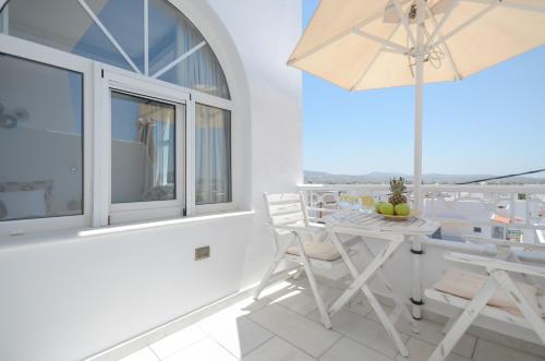 a white balcony with a table and chairs and an umbrella at Naxos Dream Oniro Studios - Adults Only in Naxos Chora