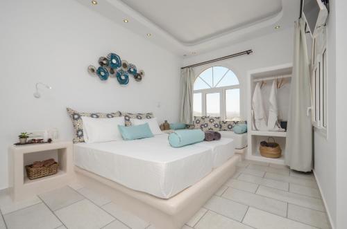 a white bedroom with a large white bed with blue pillows at Naxos Dream Oniro Studios - Adults Only in Naxos Chora