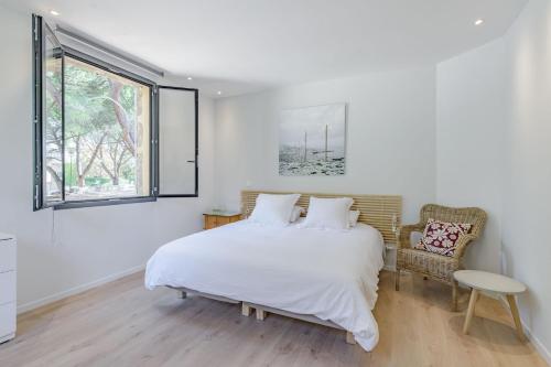 a white bedroom with a bed and a window at La maison du Boulodrome in La Bruguière