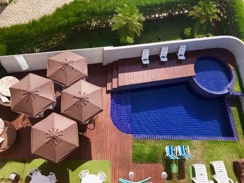 - une vue sur la piscine bordée de parasols et de chaises dans l'établissement Nord Easy Camboinha, à Cabedelo