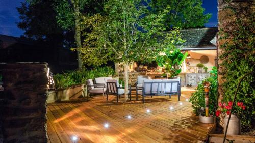 un patio con sillas y una mesa en una terraza de madera. en Ecrin du Ségala, en Tauriac-de-Naucelle