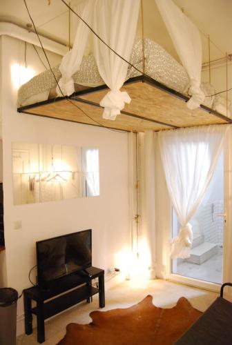 un salon avec une grande fenêtre et un lustre dans l'établissement Arty 20m² district of BATIGNOLLES, à Paris