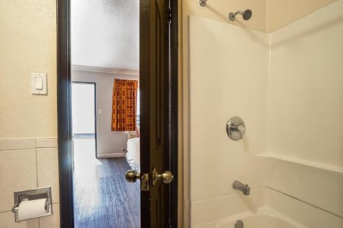 a bathroom with a shower with a door open at Value Inn Hollywood in Los Angeles
