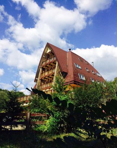 a large wooden building with a red roof at Pension Casa Vanatorilor in Băile Olăneşti